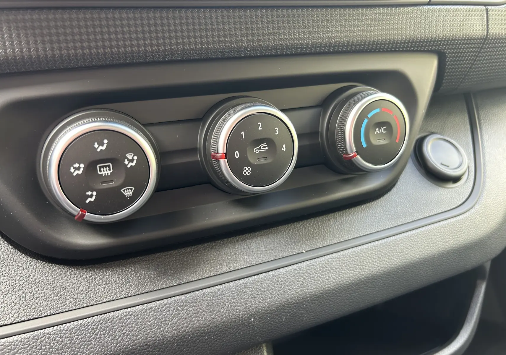 Gros plan sur les commandes de climatisation manuelle du Renault Trafic Combi blanc, avec réglages de ventilation et A/C.