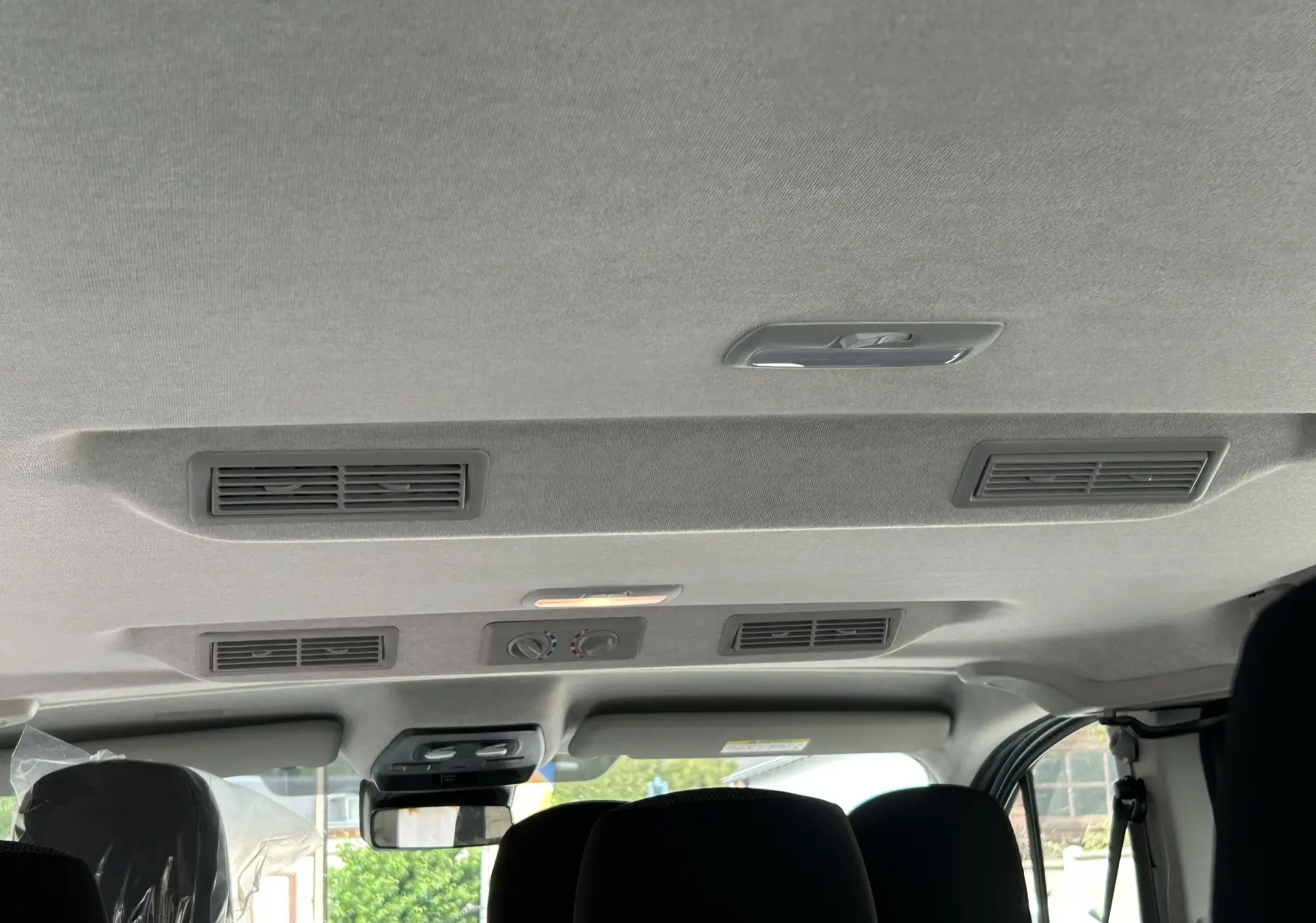 Vue intérieure du plafond et des aérateurs arrière du Renault Trafic Combi blanc Glacier, avec commandes de climatisation manuelle.