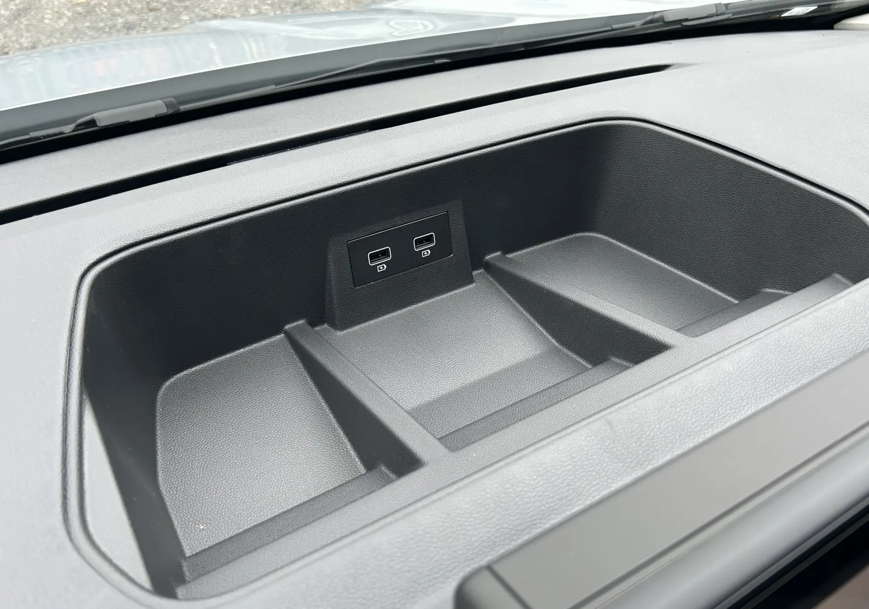 Vue rapprochée de la console de rangement noire avec deux ports USB dans le tableau de bord du Renault Trafic Combi blanc.