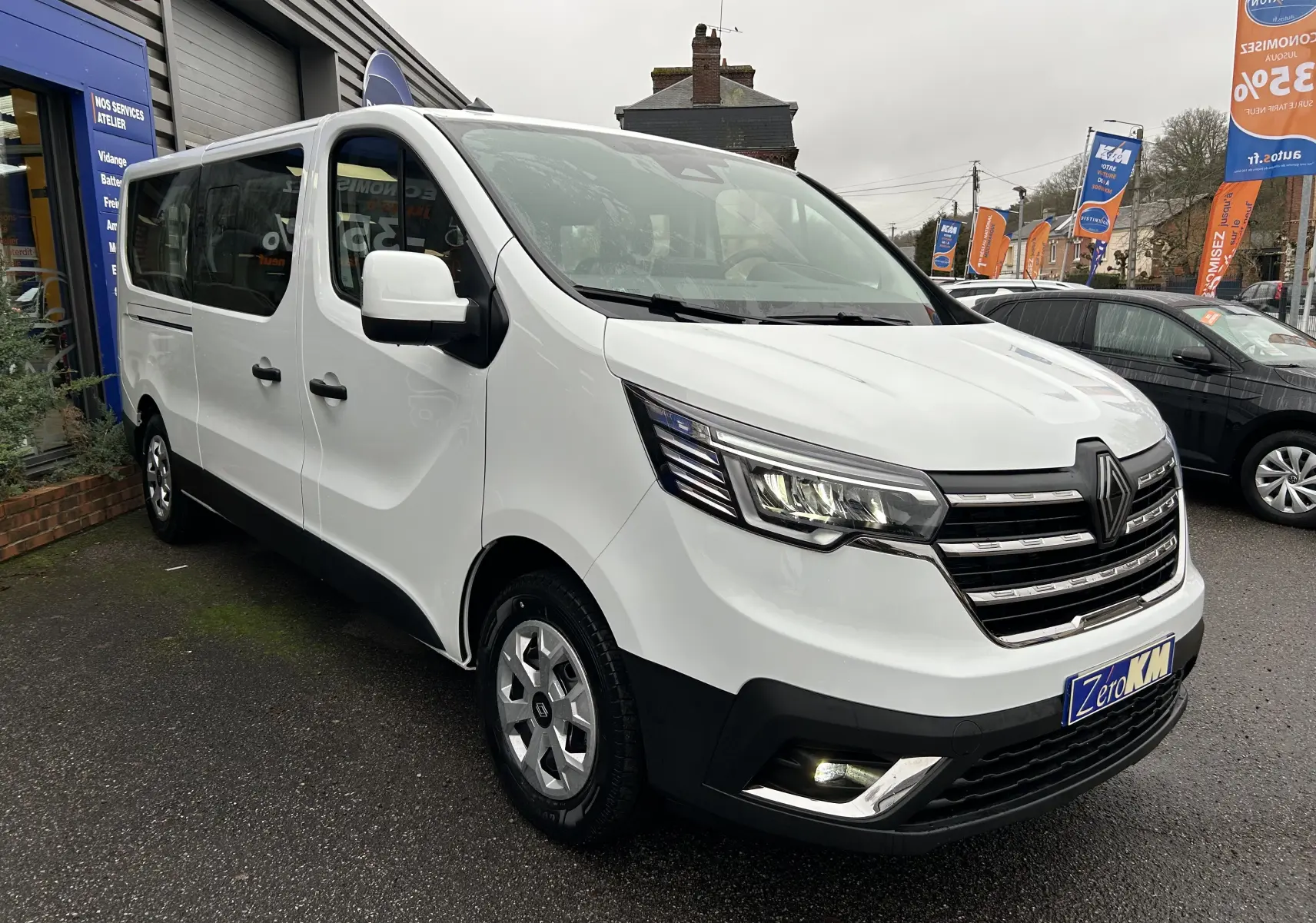 Vue 3/4 avant d’un Renault Trafic Combi blanc glacier, avec porte latérale coulissante et jantes argentées visibles.