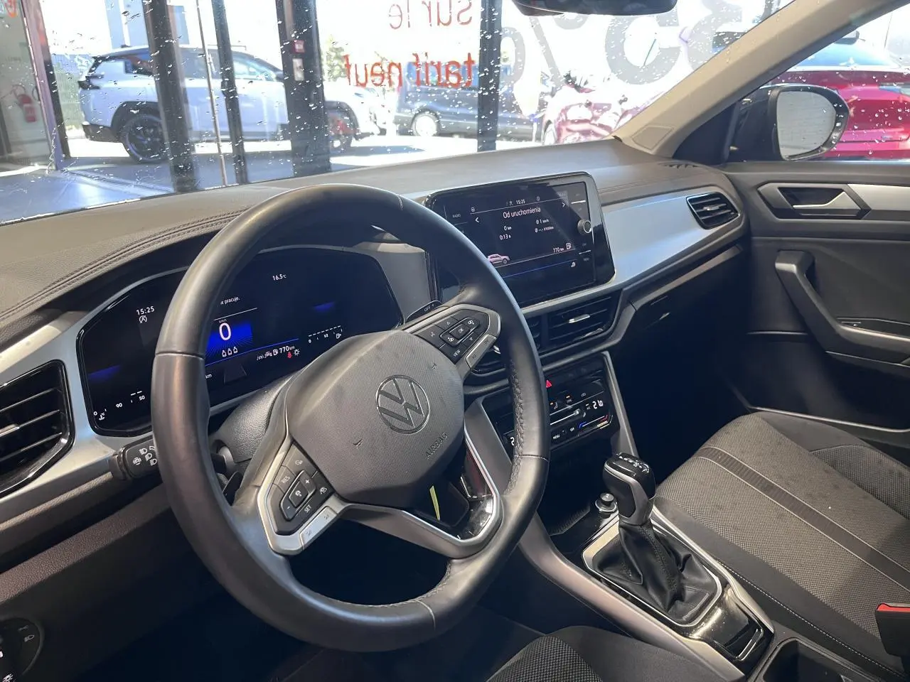 Intérieur du Volkswagen T-Roc 2025 vu côté conducteur, tableau de bord noir avec écran tactile et volant multifonction.