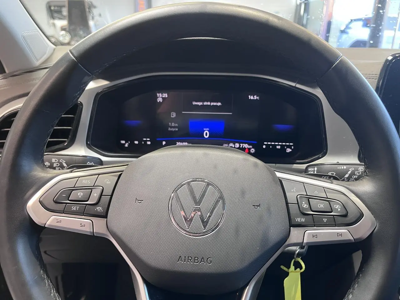 Vue rapprochée du volant en cuir noir multifonction du Volkswagen T-Roc 2025 avec tableau de bord digital allumé.