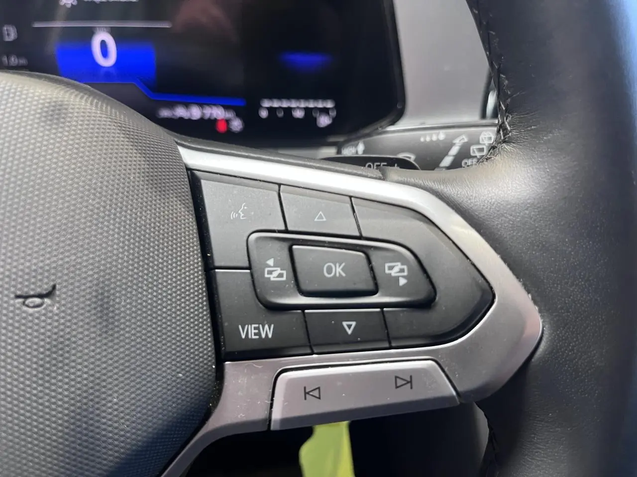 Gros plan sur les commandes multifonctions à gauche du volant cuir du Volkswagen T-Roc Deep Black Pearlescent 2025.