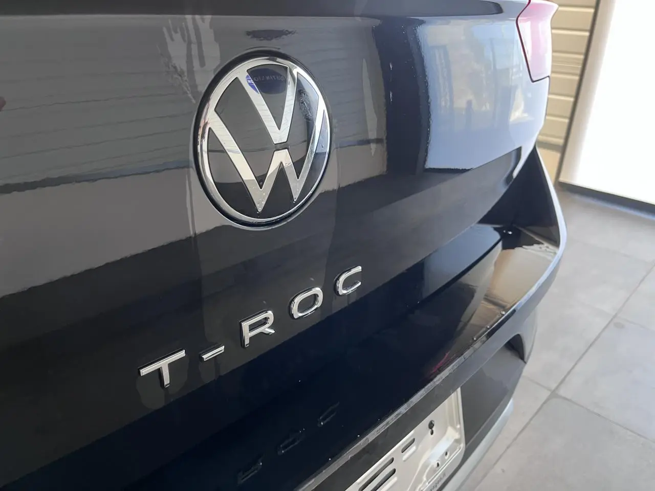 Gros plan sur l'arrière noir profond d'un Volkswagen T-Roc avec logo VW et lettrage T-ROC visible.