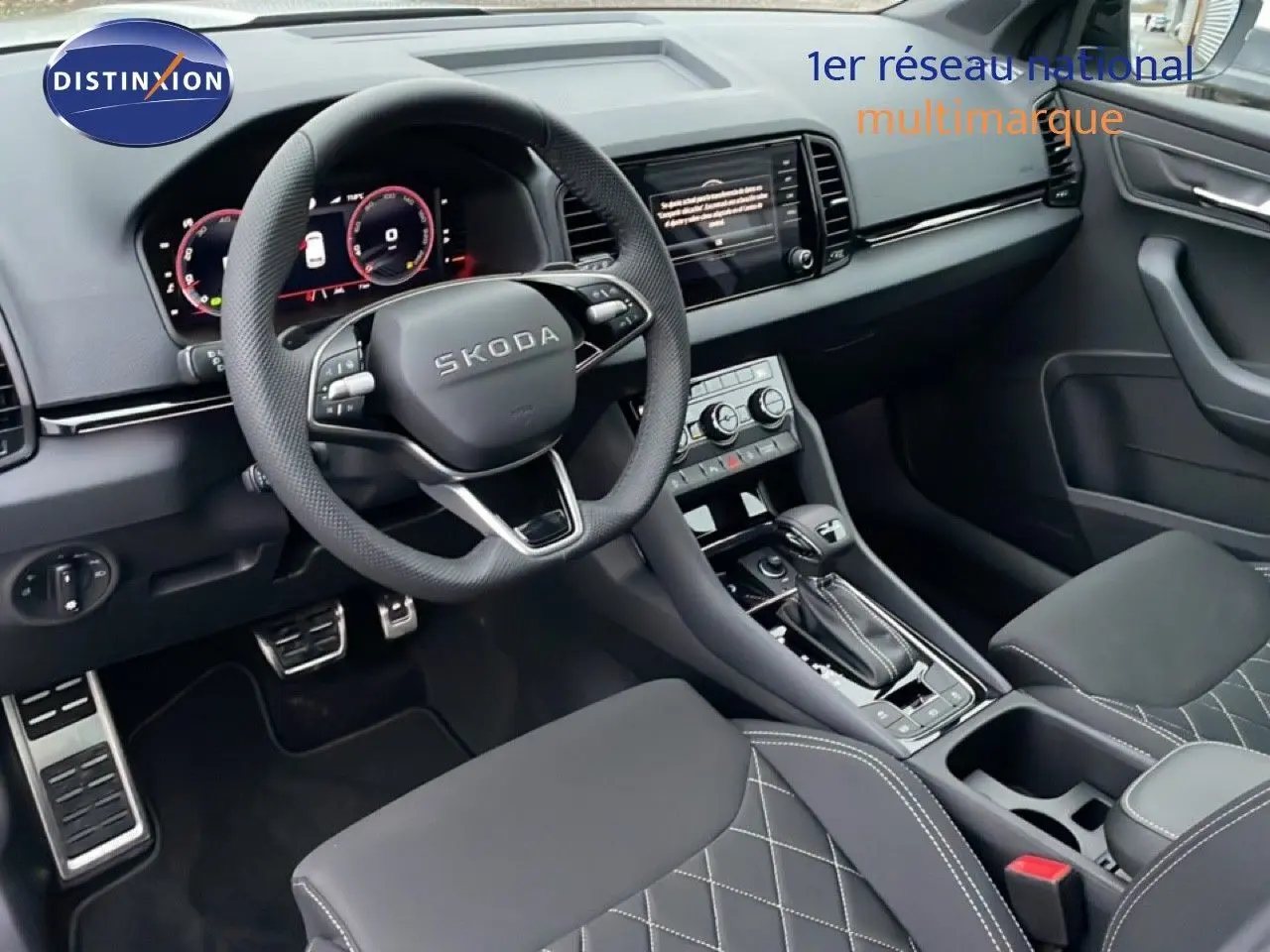 Vue intérieure du poste de conduite du Skoda Karoq gris argent 2025, avec volant multifonction et sellerie tissu noire matelassée.