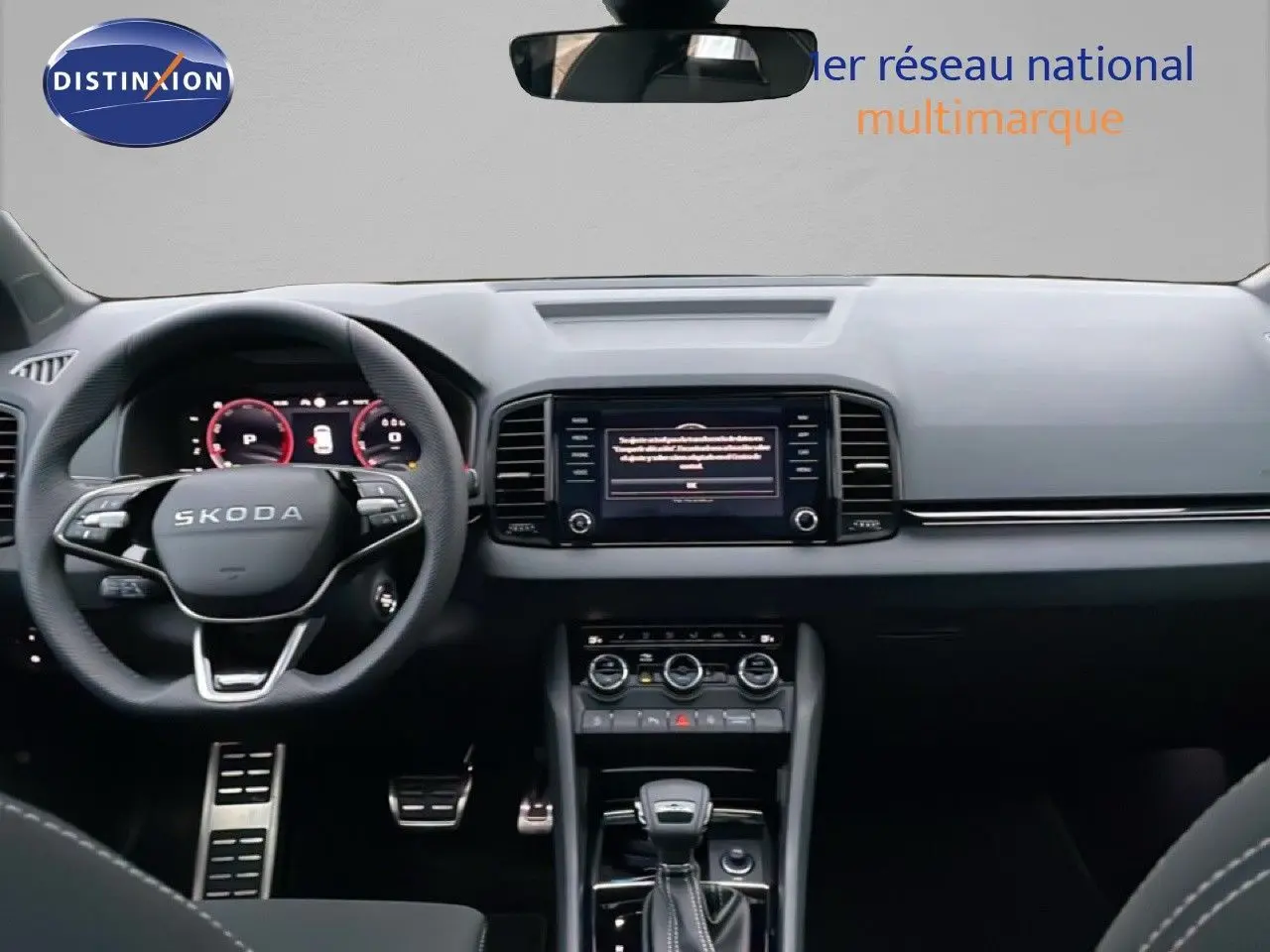 Vue intérieure avant du Skoda Karoq 1.5 TSI 2025, tableau de bord noir avec écran central tactile et volant multifonction.