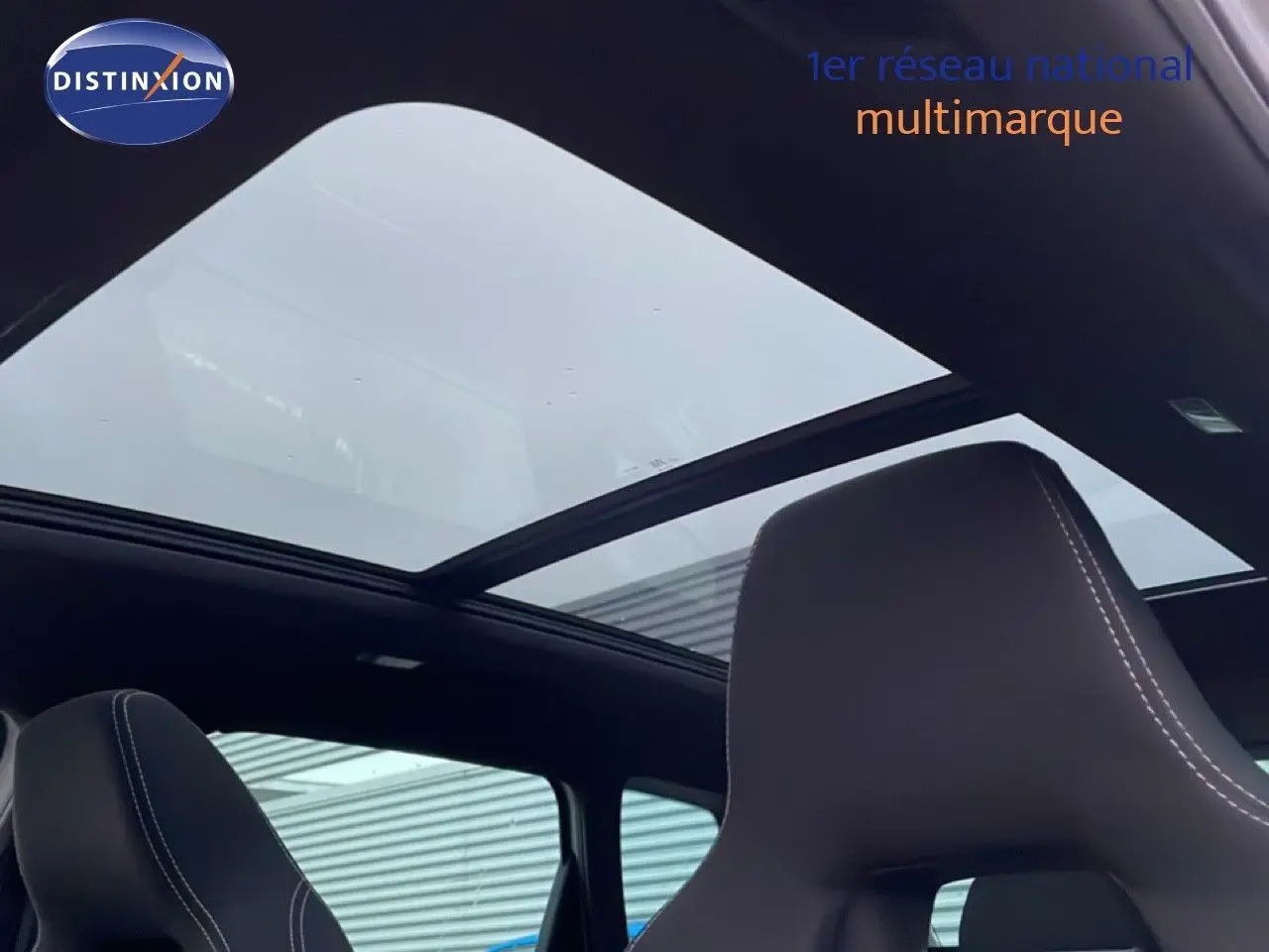 Toit panoramique ouvert vu de l'intérieur sur un Skoda Karoq gris argent 2025, sièges avant en cuir noir.
