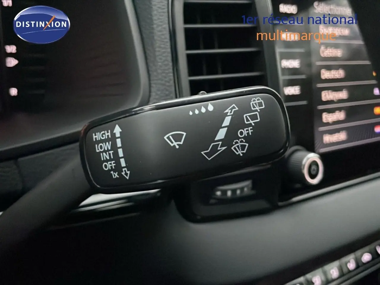 Gros plan sur la commande des essuie-glaces du Skoda Karoq gris argent, avec tableau de bord et écran tactile en arrière-plan.