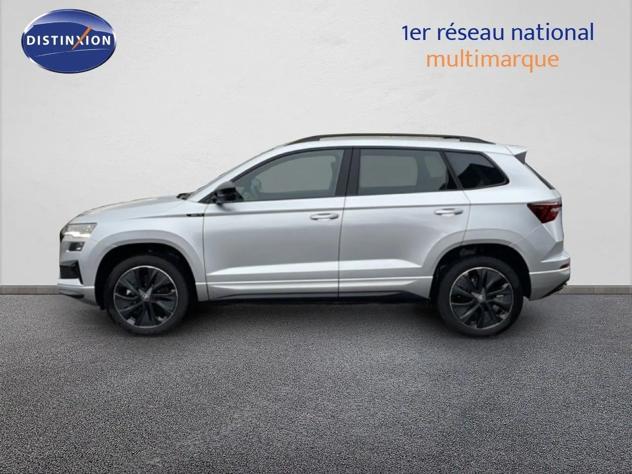 Vue de profil côté gauche d'un Skoda Karoq gris argent métallisé avec jantes noires et toit ouvrant.