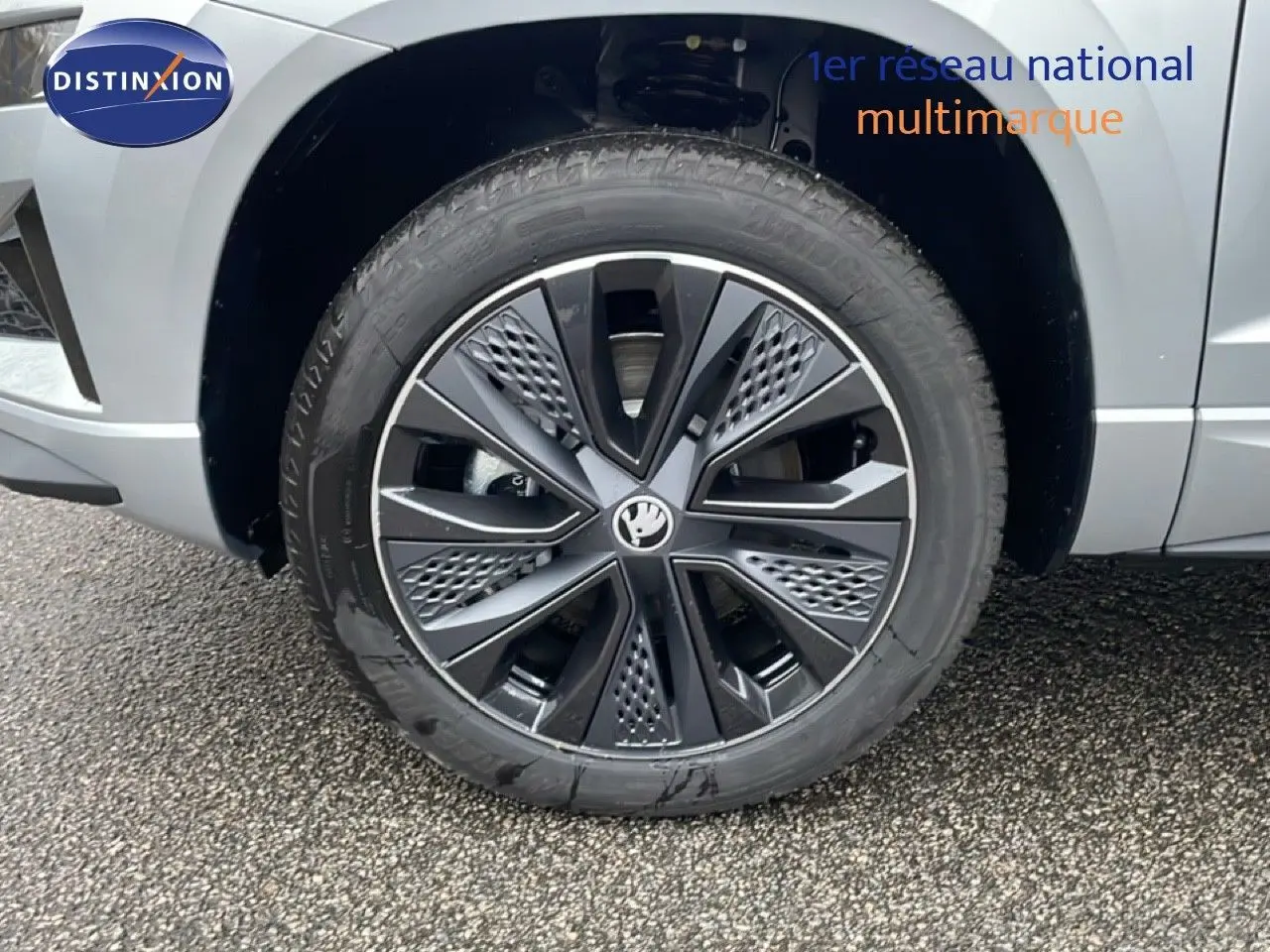 Gros plan sur la roue avant droite d’un Skoda Karoq gris argent métal, mettant en valeur la jante noire au design moderne.