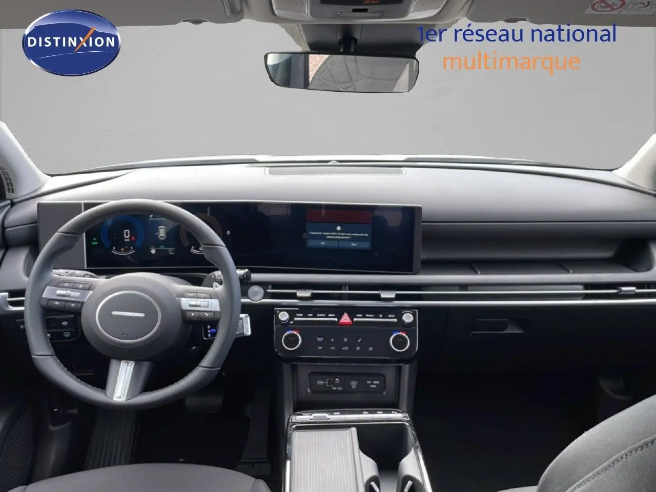 Vue intérieure avant du Hyundai Tucson 2026, tableau de bord noir avec écran large et volant multifonction.