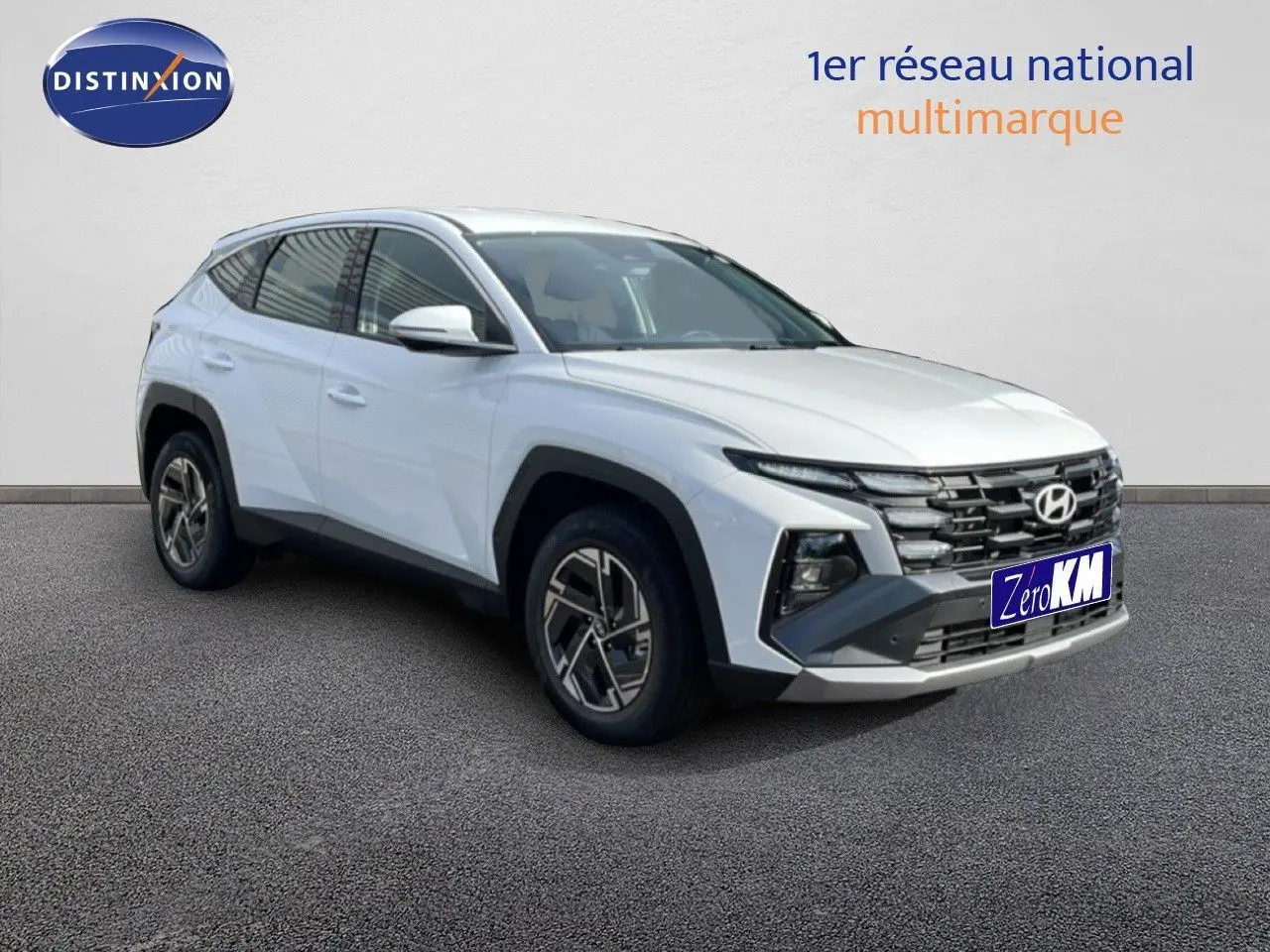 Hyundai Tucson blanc Atlas en 3/4 avant droit, SUV hybride avec calandre noire et jantes bi-ton.