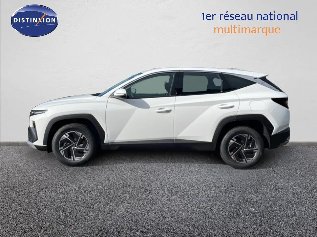 Profil droit d’un Hyundai Tucson blanc Atlas 2026, version hybride essence, avec jantes bi-ton et lignes anguleuses marquées.