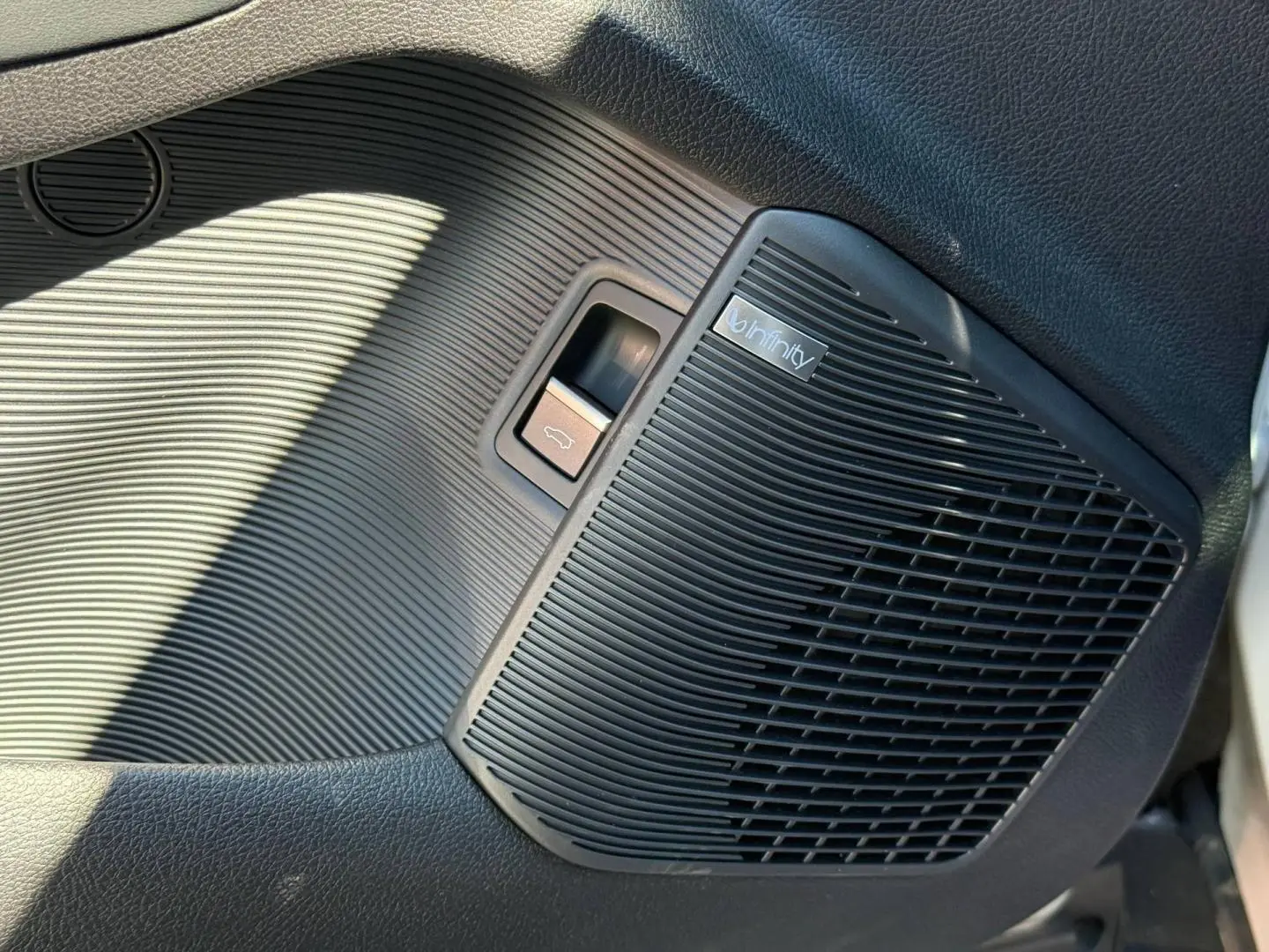 Gros plan sur le haut-parleur Infinity noir intégré dans la porte intérieure côté gauche du BYD SEAL U 1.5 DM-i 218ch Boost.