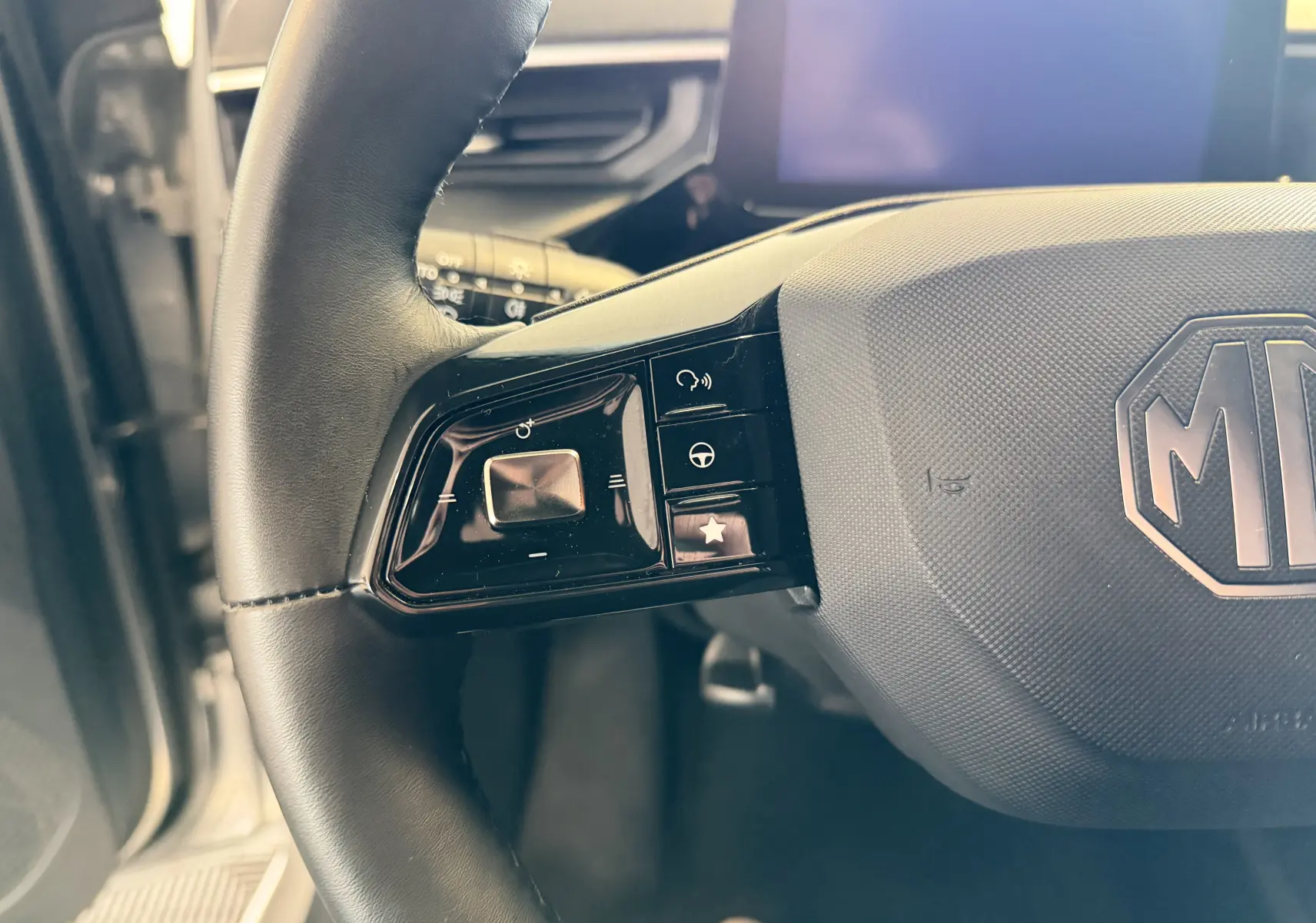 Gros plan sur la partie gauche du volant noir du MG3 2025, avec commandes intégrées et logo MG central.