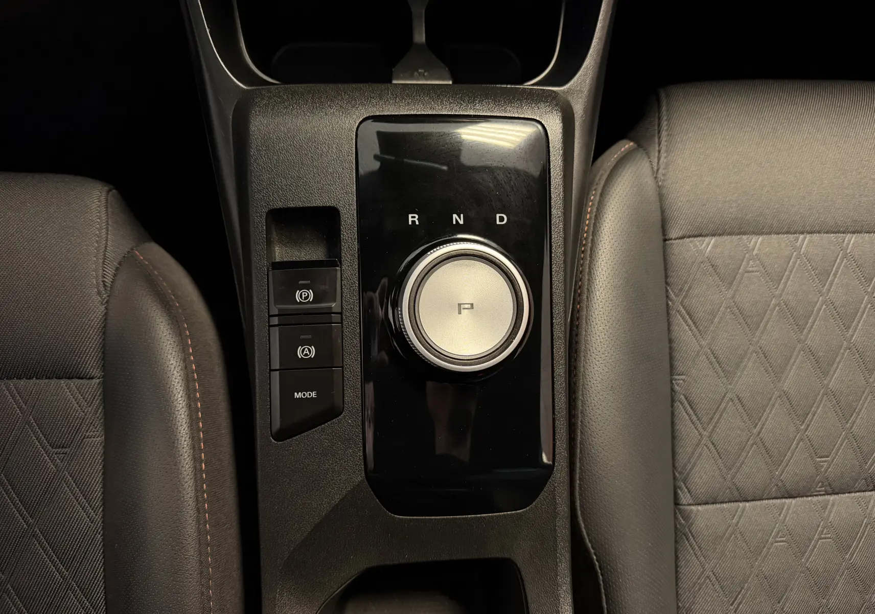 Gros plan sur la console centrale avec la molette de boîte auto et les sièges en similicuir et tissu gris du MG3 1.5 L Hybrid+ 2025.