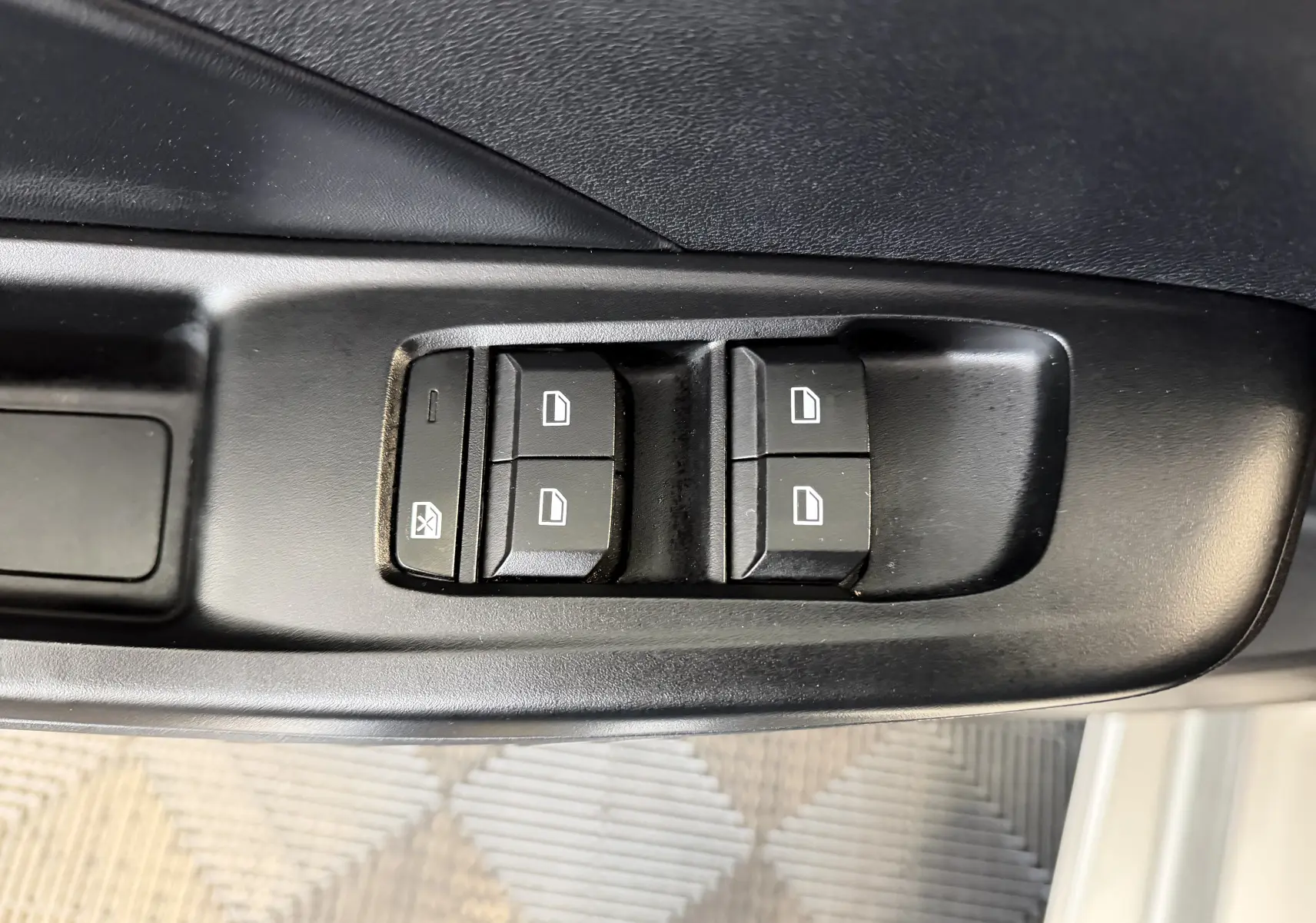 Gros plan sur les commandes des vitres électriques côté conducteur de la MG3 1.5 L Hybrid+ 2025 en cosmic silver.