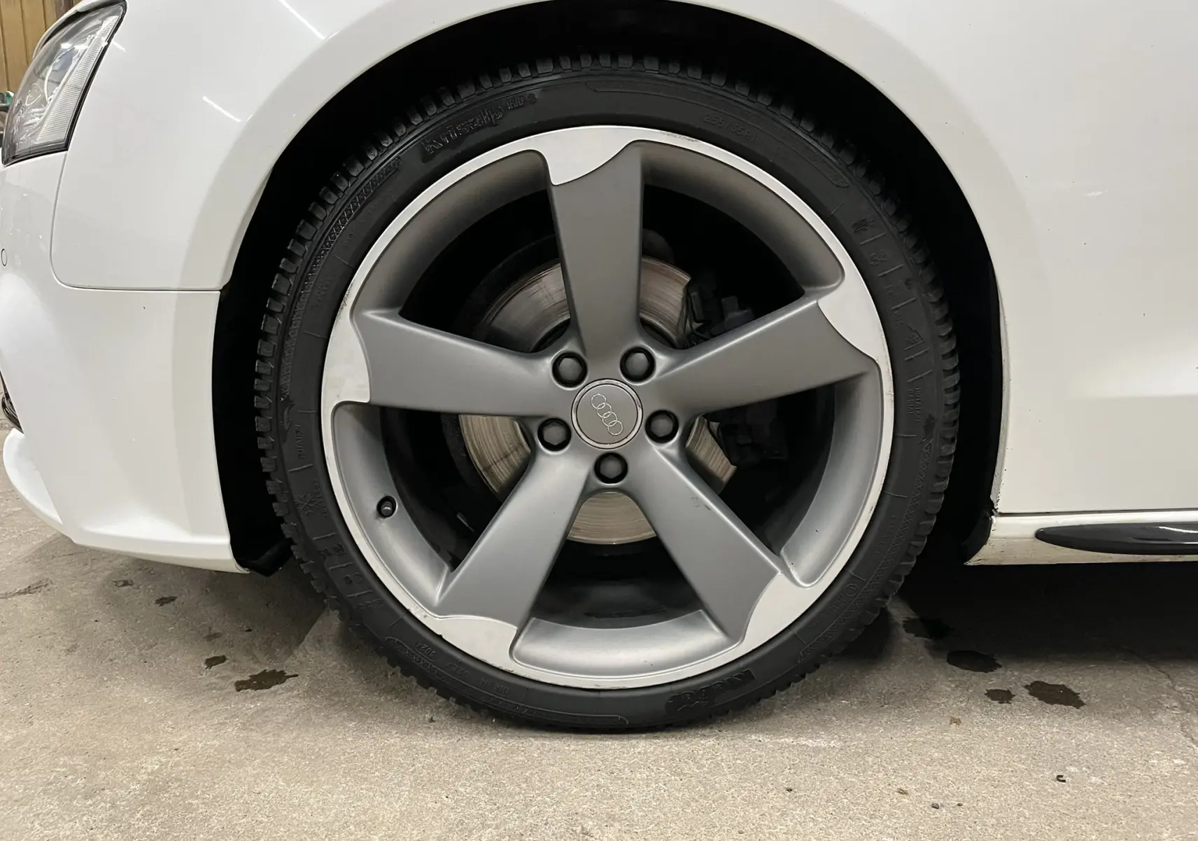 Gros plan sur la roue avant gauche grise à cinq branches de l'Audi A5 Sportback blanche de 2015.