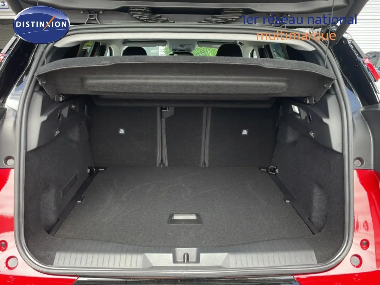 Coffre ouvert vu de l'arrière d'un Citroën C5 Aircross Hybrid rouge rubis métal, montrant l'espace de chargement vide.