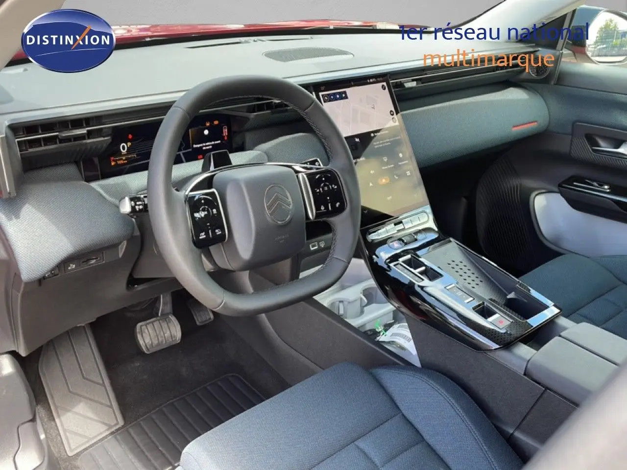 Vue intérieure avant du Citroën C5 Aircross Hybrid rouge rubis, mettant en valeur le tableau de bord et la console centrale tactile.