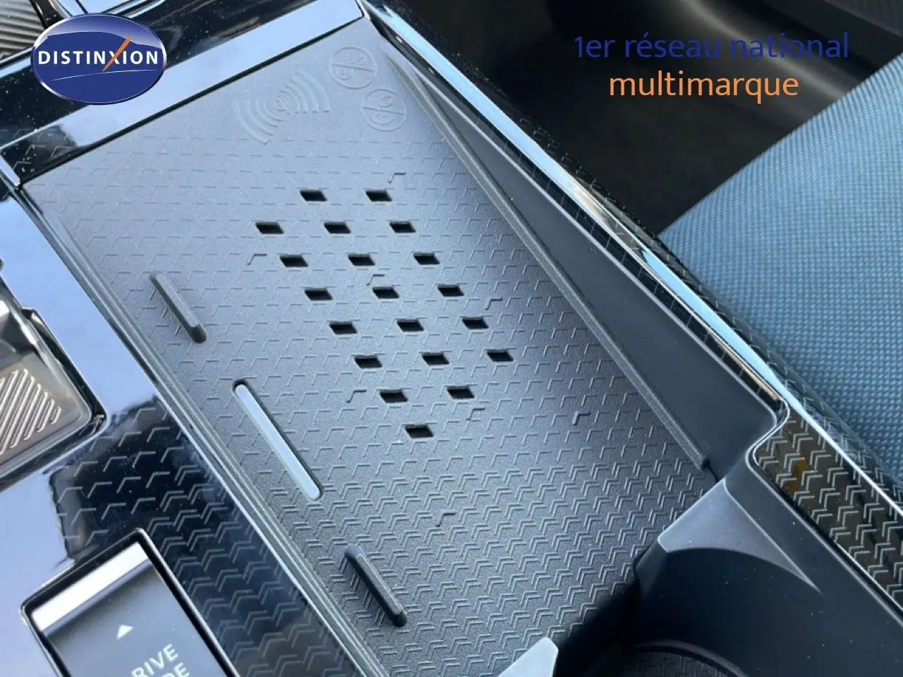 Détail du chargeur sans fil et console centrale noire du Citroën C5 Aircross Hybrid 2026, intérieur tissu bleu.
