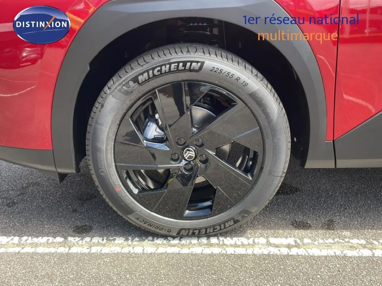Gros plan sur la roue avant droite noire du Citroën C5 Aircross Hybrid rouge rubis métal, avec jante noire brillante.
