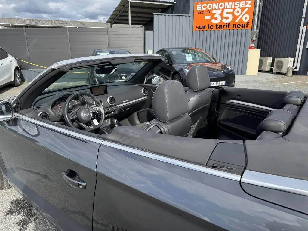 Vue côté gauche intérieur d'un cabriolet Audi A3 gris avec capote noire repliée et tableau de bord moderne.