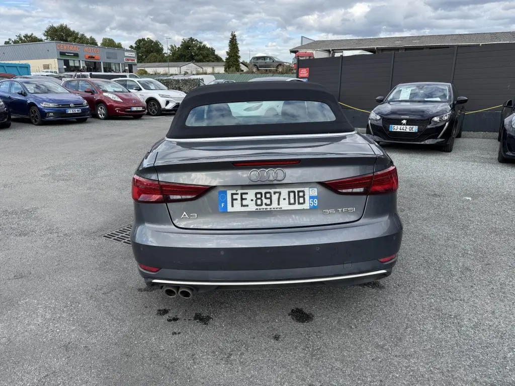Vue arrière d'une Audi A3 Cabriolet gris métallisé avec capote noire et double sortie d'échappement chromée.