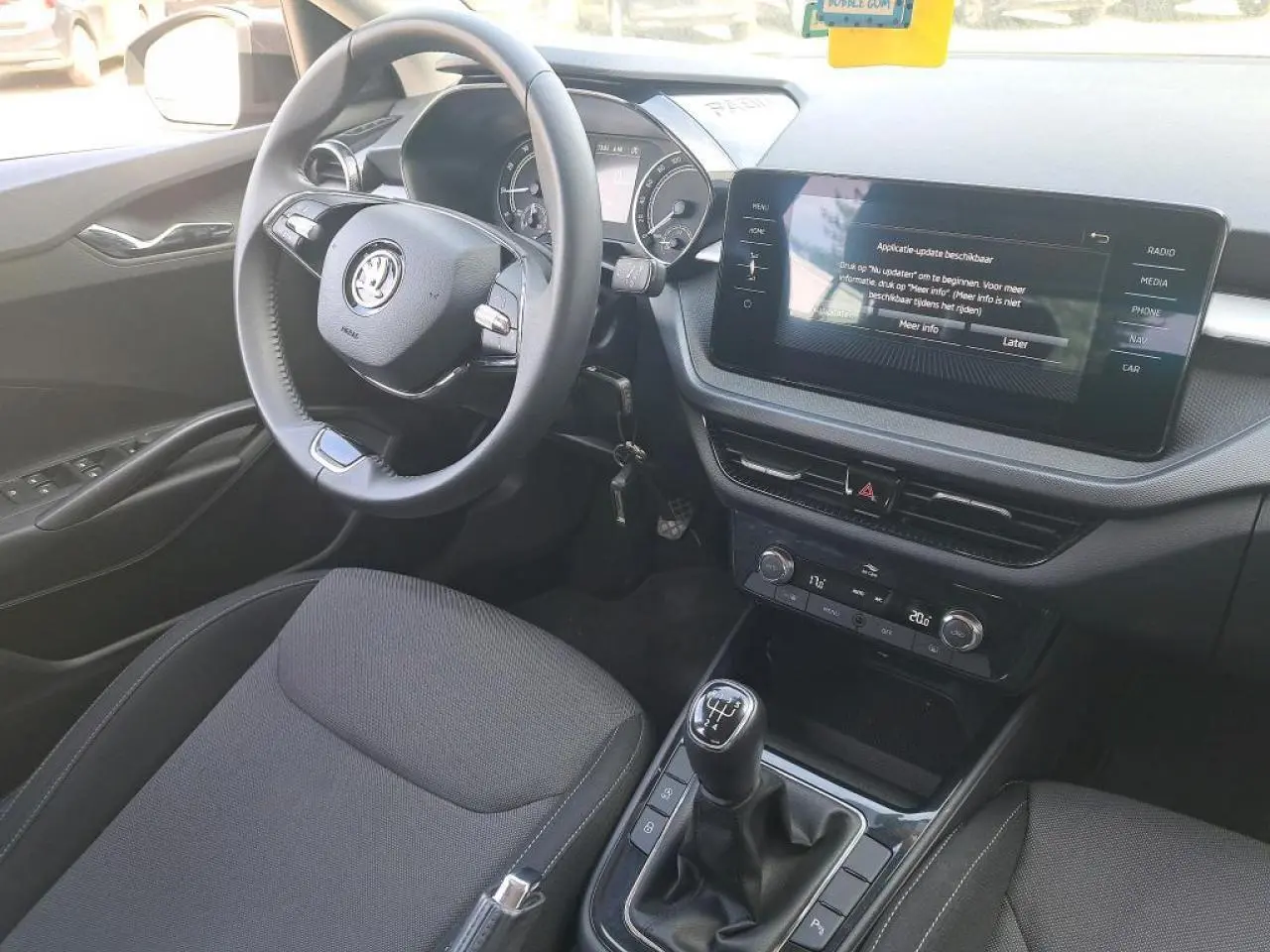 Vue intérieure côté conducteur de la Skoda Fabia 2024 noire, volant cuir, écran tactile et levier de vitesses manuel visibles.