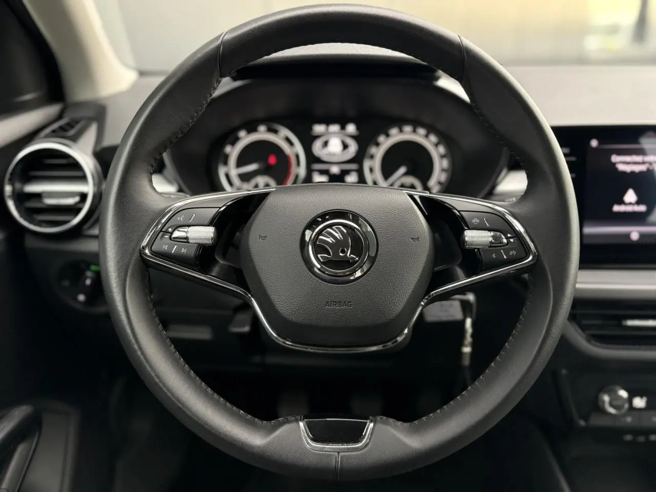 Vue 3/4 arrière droite d'une Skoda Fabia 2024 noire Magic avec hayon ouvert sur parking pavé.