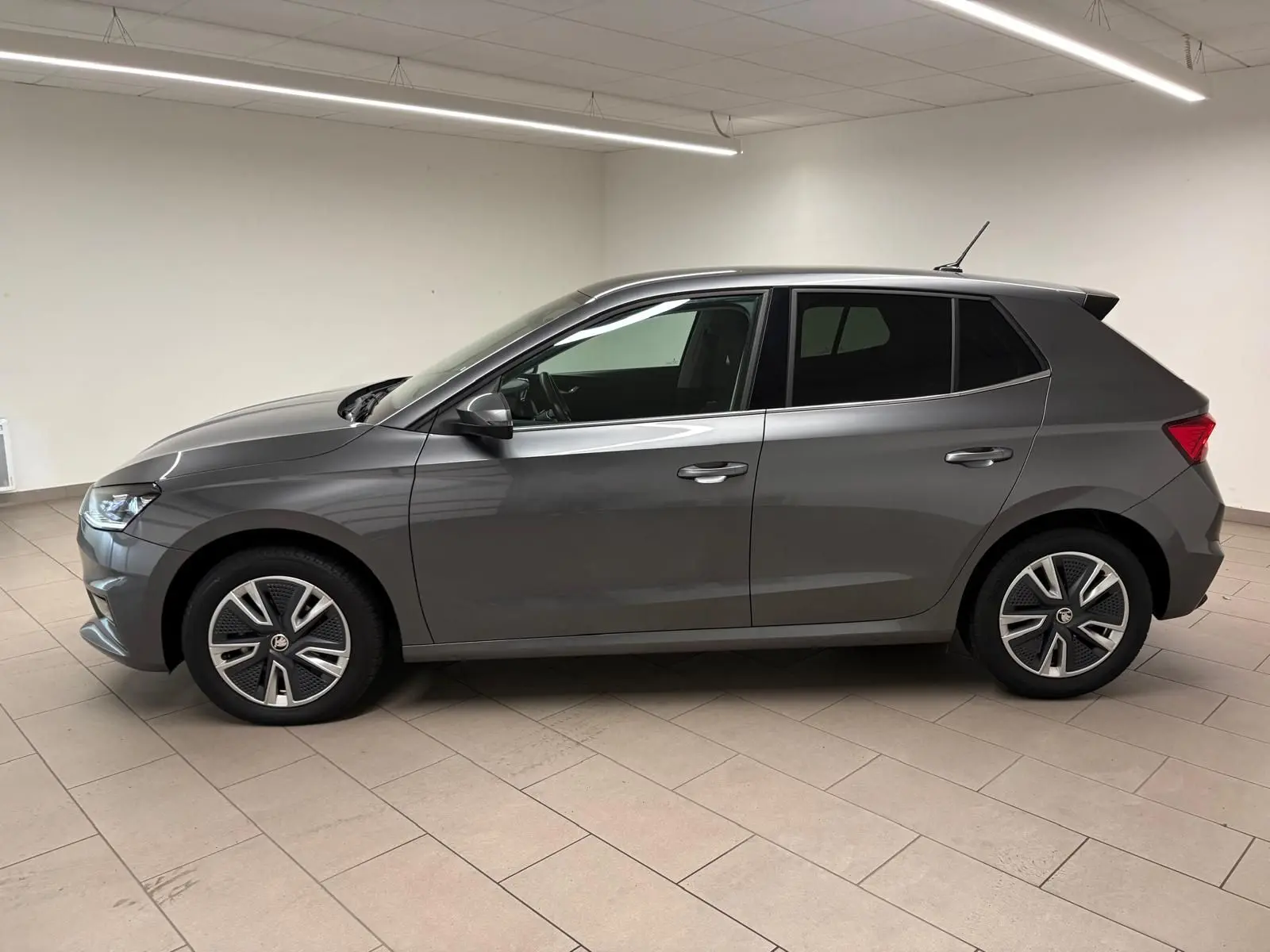 Profil côté gauche de la Skoda Fabia 1.0 TSI 95 BVM5 Style 2023 en gris graphite métallisé dans un intérieur neutre.
