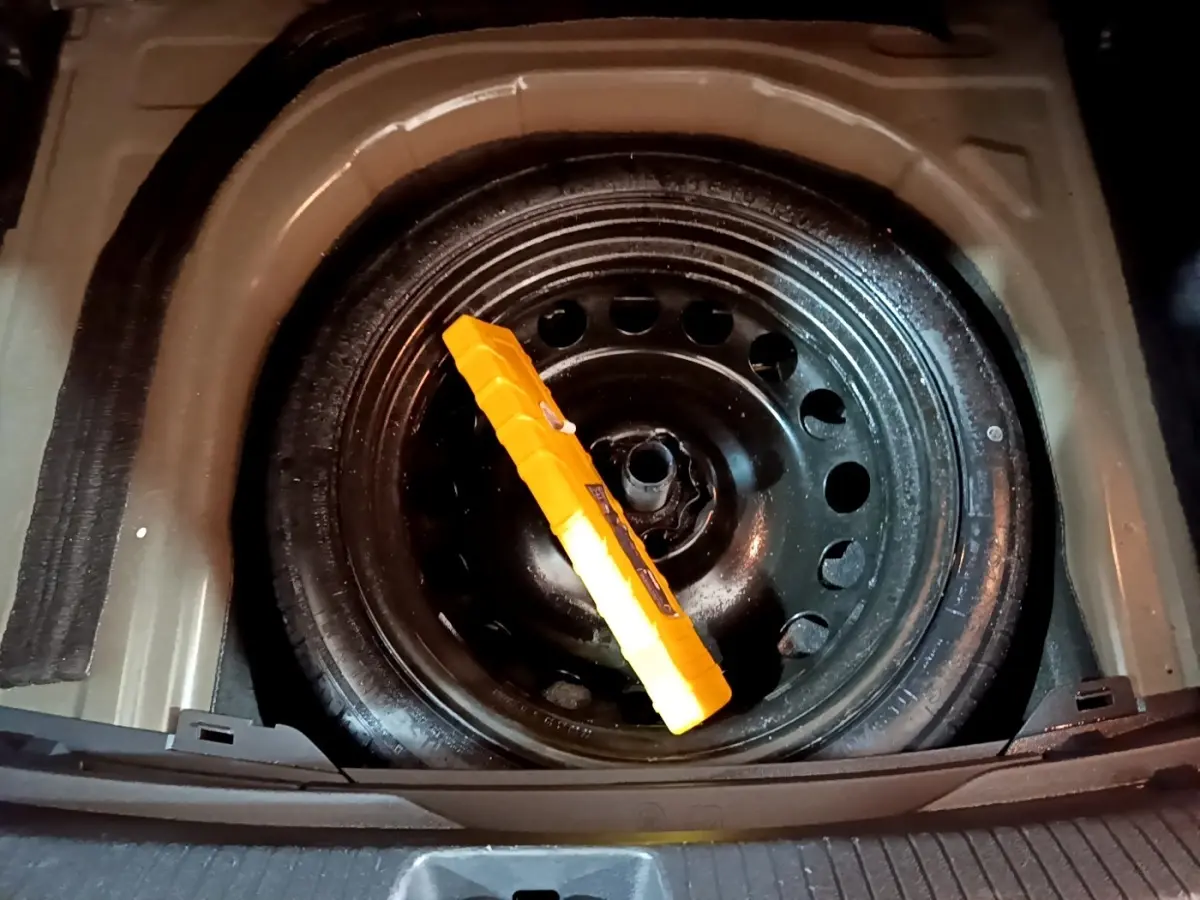 Vue plongeante sur la roue de secours noire dans le coffre d’un Volkswagen Taigo 1.0 TSI 95 Life 2023.