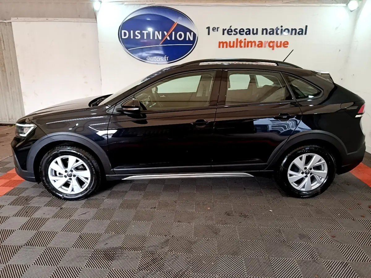 Vue de profil côté gauche d'un Volkswagen Taigo noir 2023 avec jantes alliage et barres de toit noires.