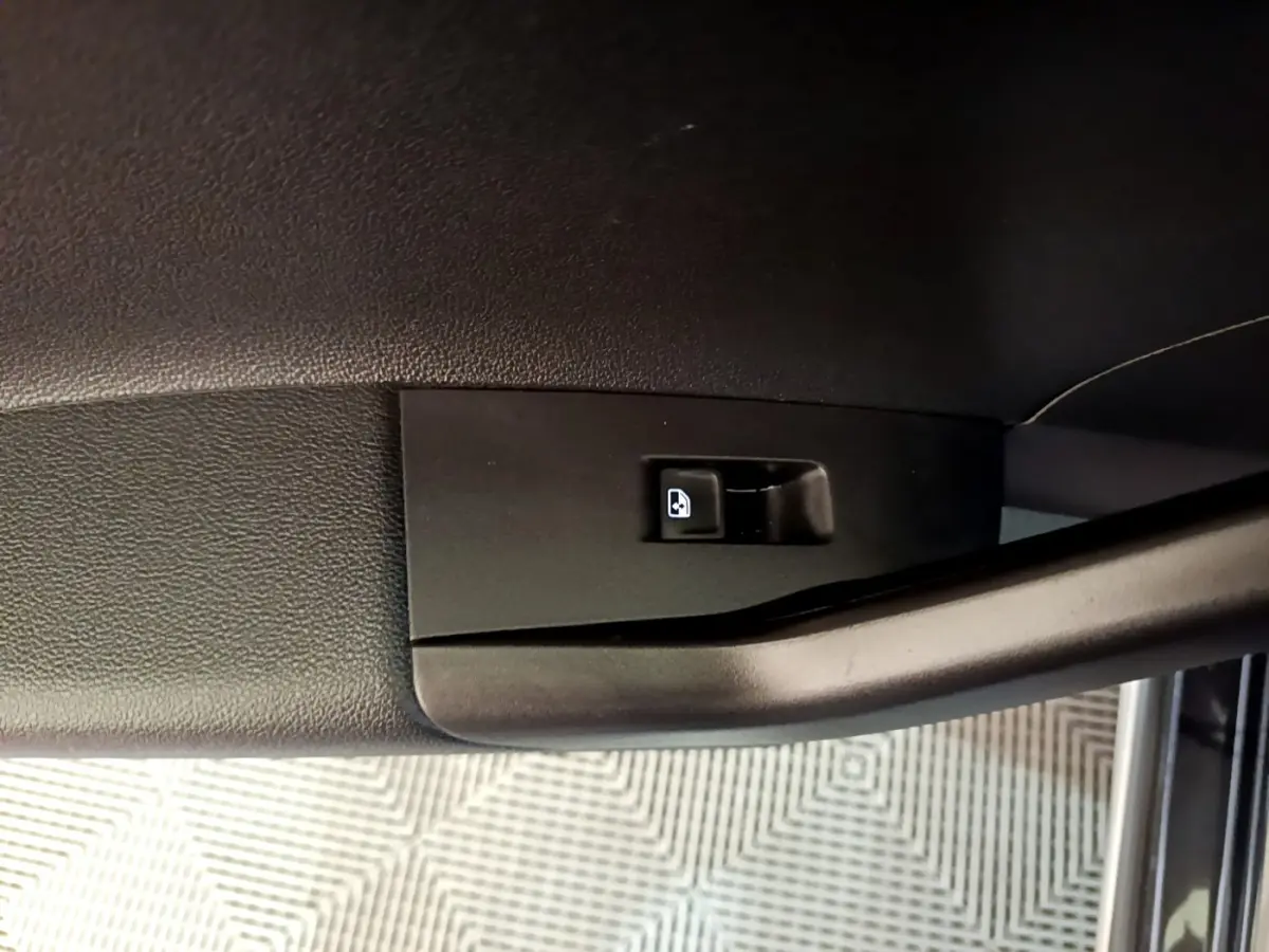 Gros plan sur la poignée intérieure noire de porte côté conducteur du Volkswagen Taigo noir, avec bouton de verrouillage visible.