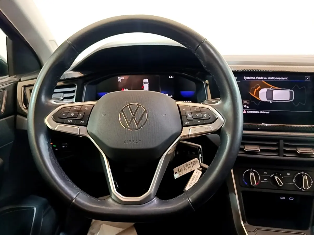 Vue intérieure centrée sur le volant cuir et alu du Volkswagen Taigo 1.0 TSI 95 Life avec écran tactile et affichage digital.