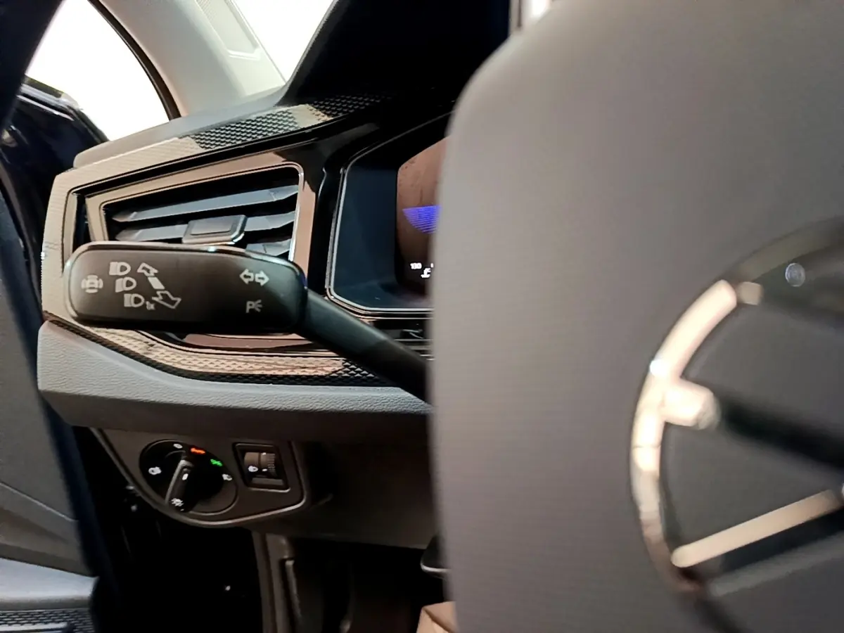 Gros plan sur la commande des clignotants et tableau de bord côté gauche du Volkswagen Taigo noir 2023.