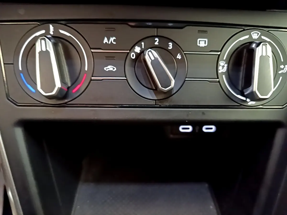 Vue rapprochée des commandes de climatisation noires du Volkswagen Taigo 2023 avec deux ports USB-C éclairés.