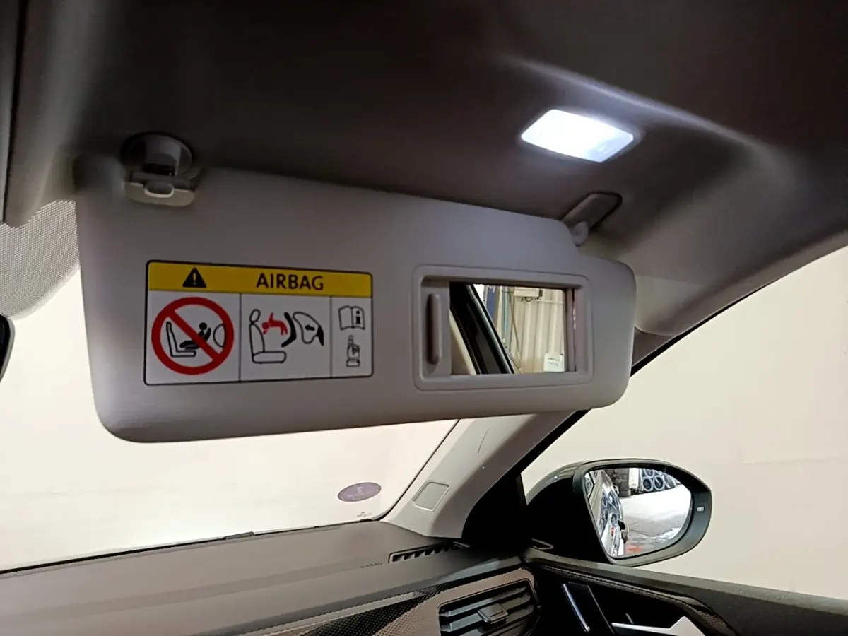 Détail intérieur montrant le pare-soleil côté conducteur avec miroir et rétroviseur extérieur noir du Volkswagen Taigo 2023.