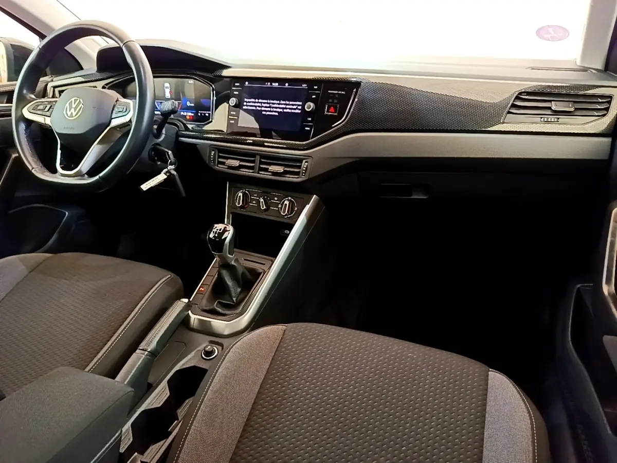 Vue intérieure avant du Volkswagen Taigo 1.0 TSI 95 Life 2023, montrant le volant cuir alu, la boîte manuelle et l’écran tactile central.