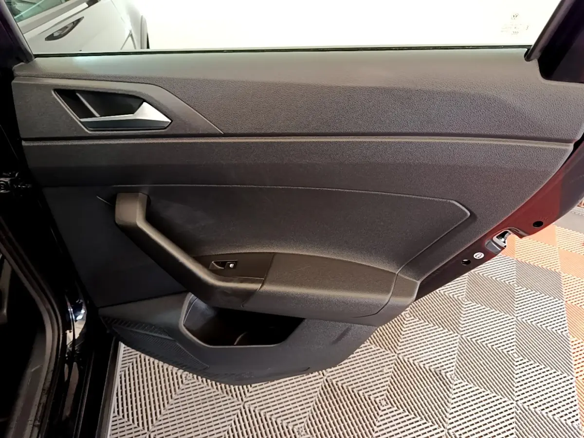 Vue intérieure de la porte arrière gauche noire du Volkswagen Taigo 2023, avec poignée et commande de vitre.