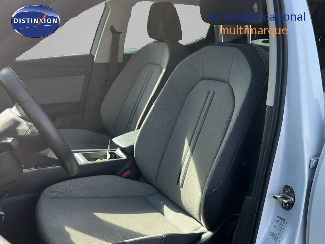 Vue intérieure côté conducteur d’une SEAT LEON 2.0TDI 115CH STYLE XL 2025 avec sièges tissu gris et portière blanche ouverte.