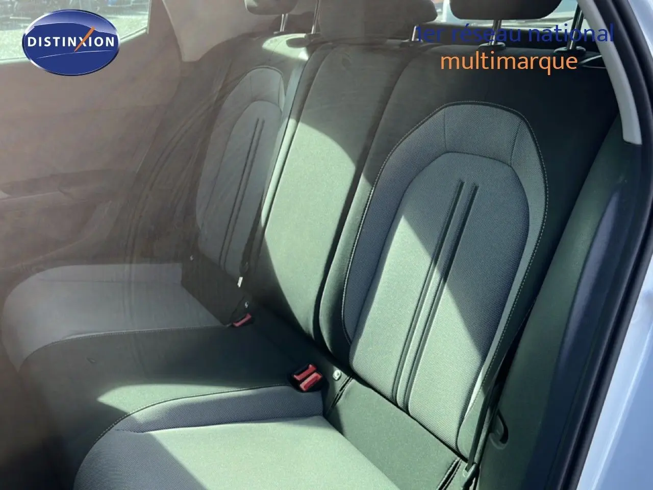 Vue intérieure montrant les sièges arrière en tissu gris noir d'une SEAT LEON blanc neige, porte arrière ouverte.