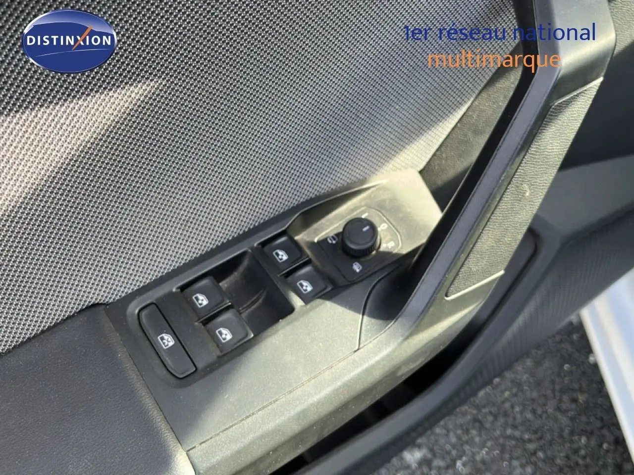 Gros plan sur la commande des vitres électriques côté conducteur d'une SEAT LEON blanc neige, intérieur tissu gris.