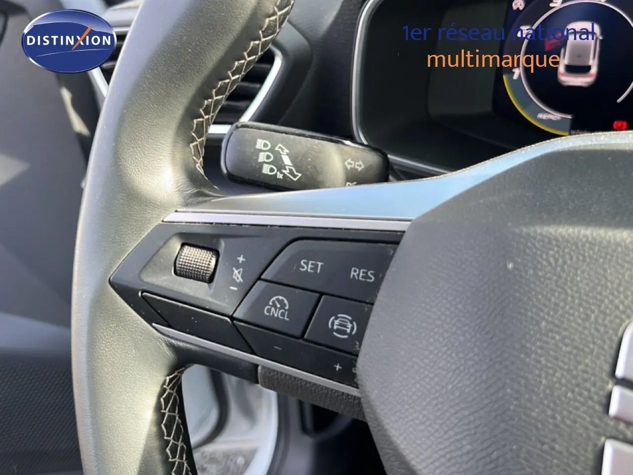 Gros plan sur le volant côté gauche de la SEAT LEON blanc neige, avec commandes intégrées visibles.