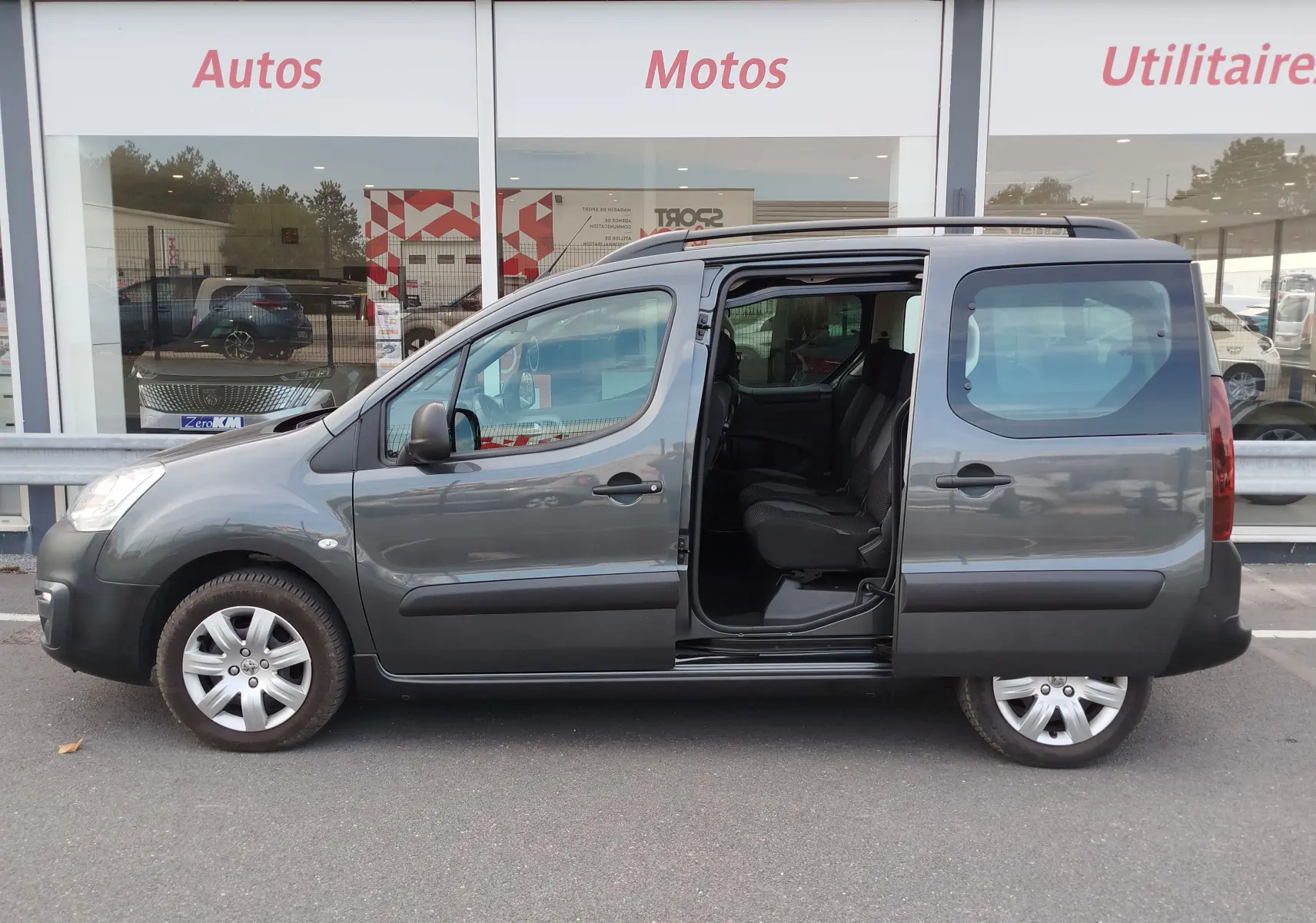 Vue latérale droite d’un Peugeot Partner Tepee gris foncé 2017 avec porte coulissante ouverte dévoilant l’intérieur et les sièges.