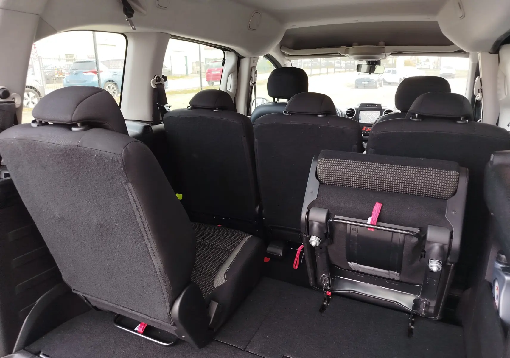 Vue intérieure arrière du Peugeot Partner Tepee gris foncé, montrant les sièges arrière dont un partiellement replié.
