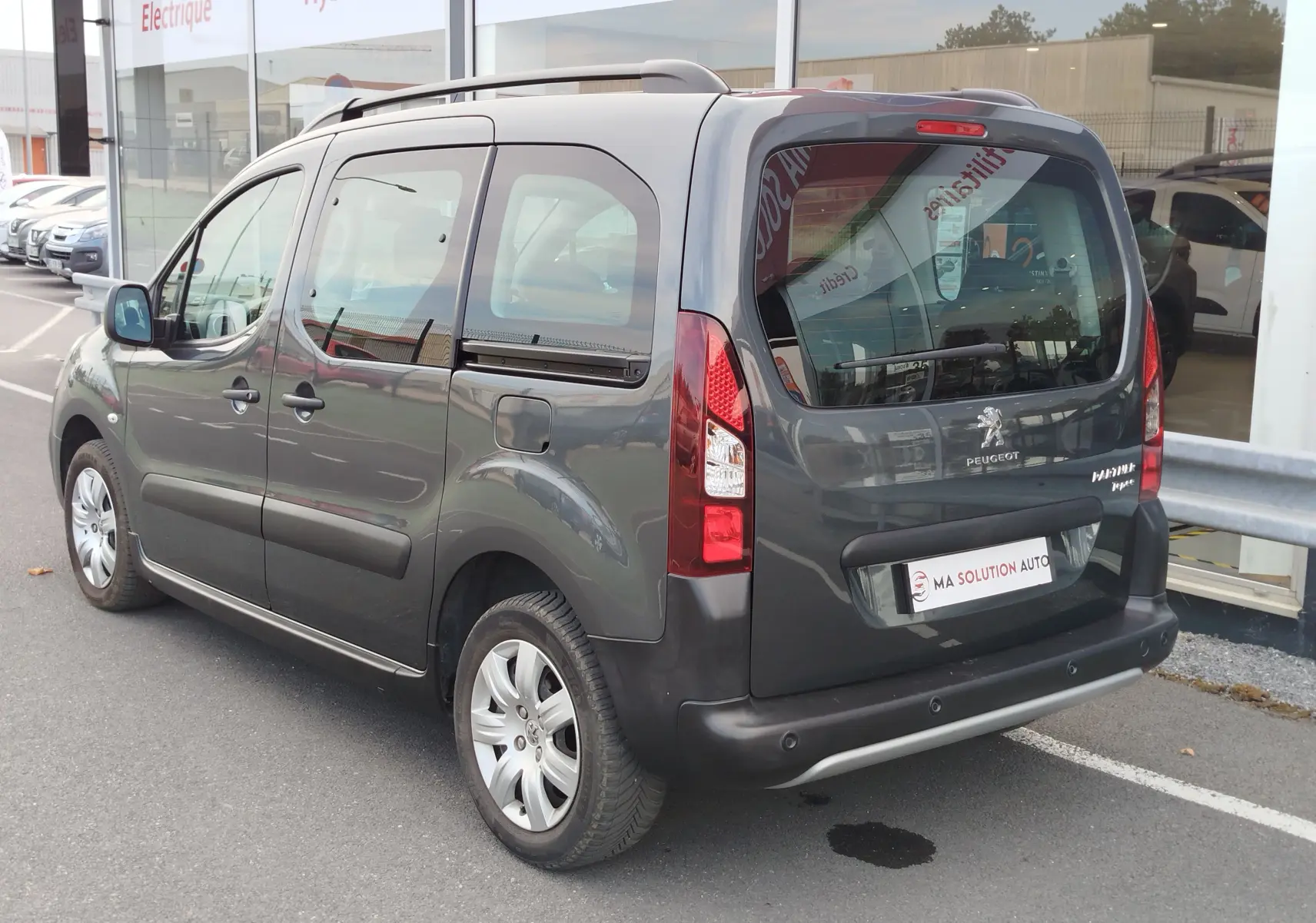 Vue 3/4 arrière droite d’un Peugeot Partner Tepee gris foncé avec toit surélevé et vitres arrière teintées.