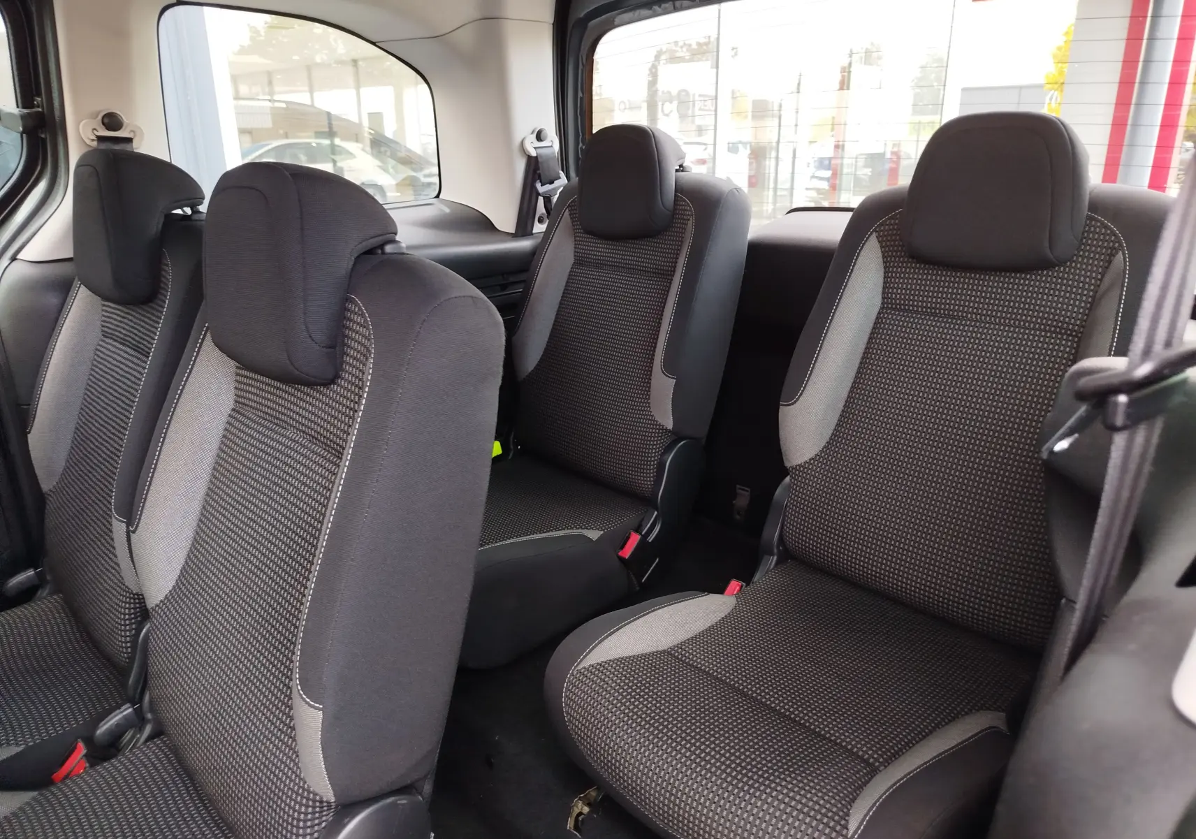Vue intérieure des sièges arrière en tissu gris foncé du Peugeot Partner Tepee 2017, version 7 places.