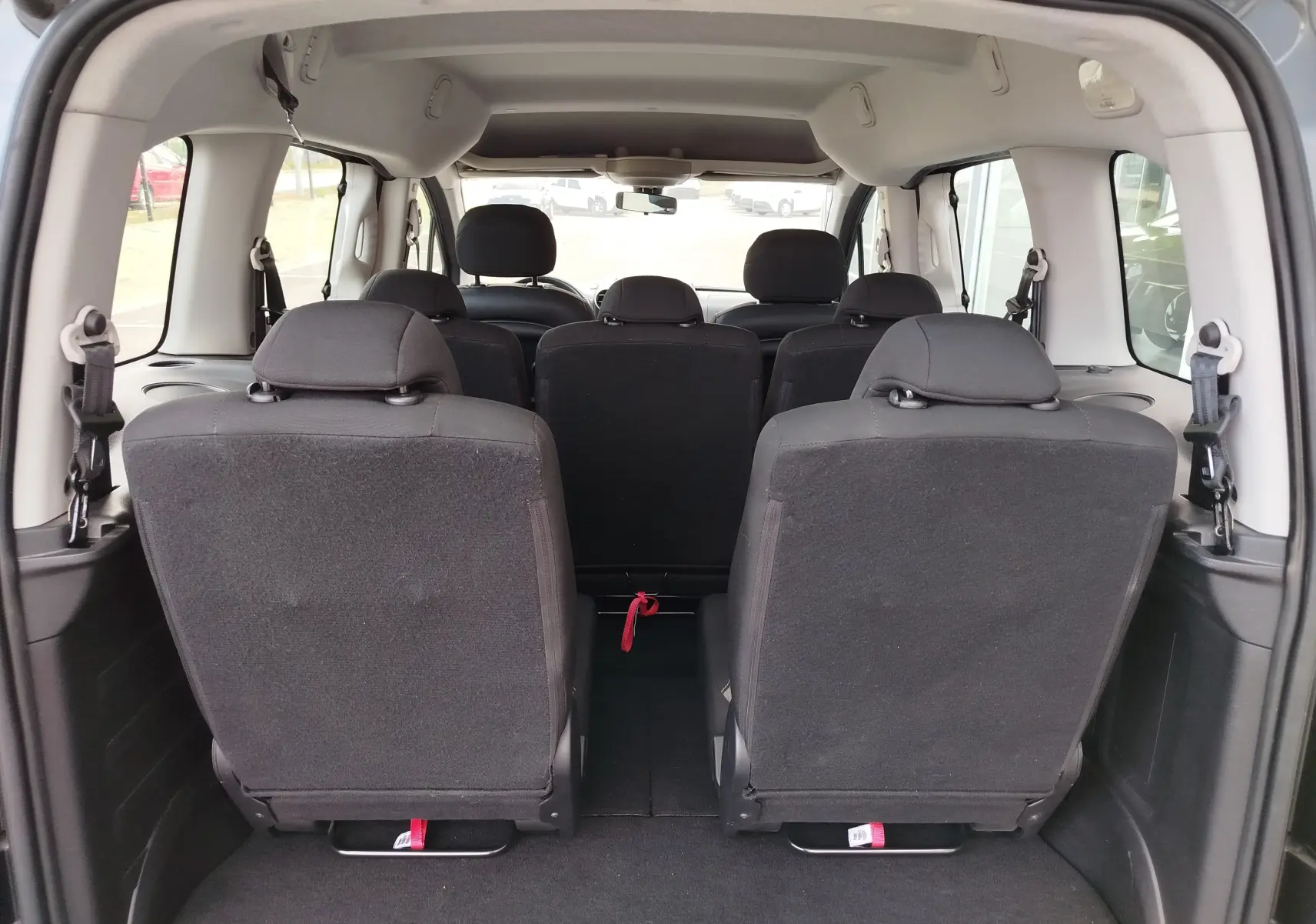 Vue arrière intérieure du Peugeot Partner Tepee 2017 gris foncé, montrant les sièges en tissu noir sur 3 rangées.