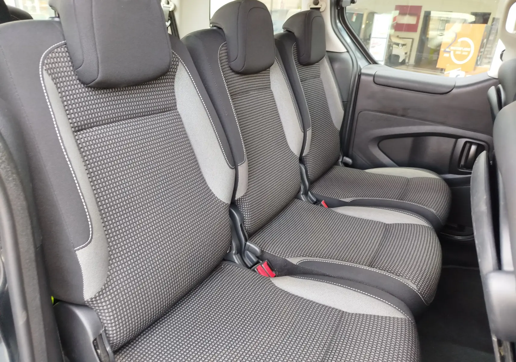 Vue intérieure côté droit montrant les trois sièges arrière en tissu gris foncé du Peugeot Partner Tepee 2017.